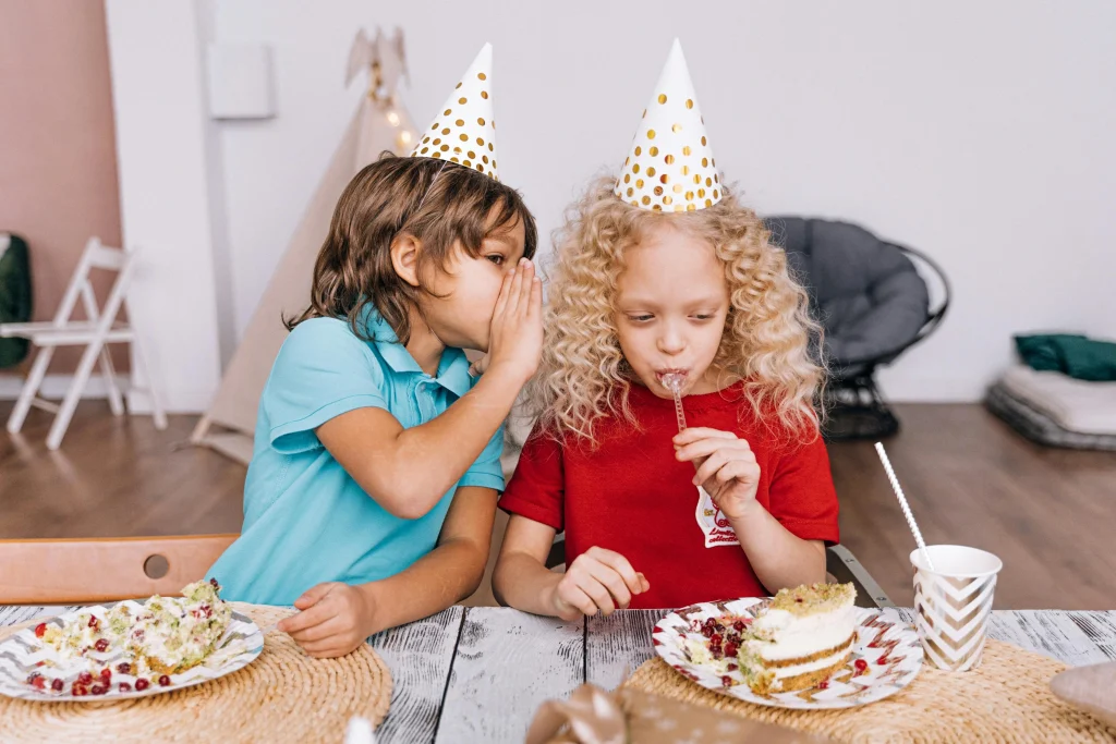 A boy whispering in the girl's ear at a kids birthday party